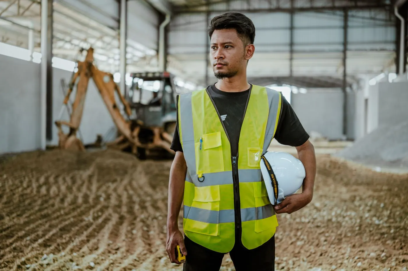 Construction worker in safety vest holding a hard hat